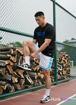 Asian man with short black buzz cut and clean-shaven face, standing casually near a green chain-link