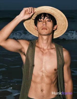 Asian man with tanned skin and short black straight hair stands in shallow water at night, adjusting