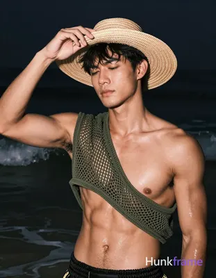 Asian man with tanned skin and short black straight hair stands in shallow water at night, adjusting