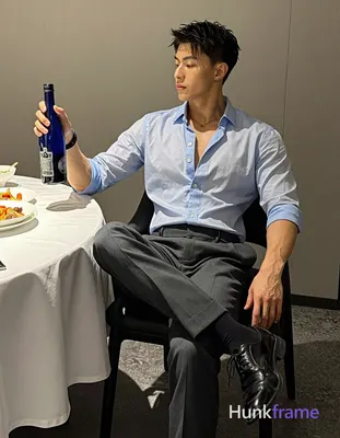 seated sideways on black chair with crossed legs left leg forward right leg back; Wearing light blue