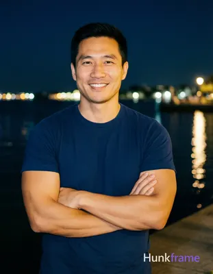 Asian man with short black hair and clean-shaven face stands confidently at a ni