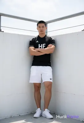 Asian man with short black buzz cut and clean-shaven face, standing leaning agai