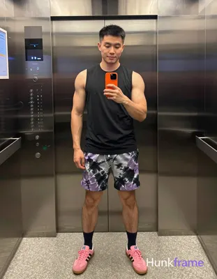 Asian man with medium-dark skin and short black straight hair stands in a full-body vertical mirror 