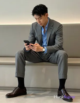 Asian man with short black textured hair and clean-shaven face, seated sideways 