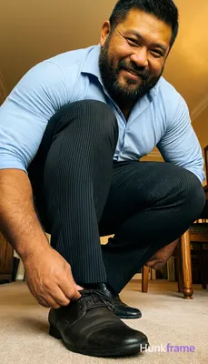 Low-angle close-up of a big hairy stocky masculine man crouching with knees bent together, torso lea