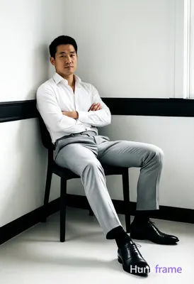Asian man with short black hair and clean-shaven face, neutral direct gaze seate