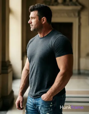 A stocky muscular adult man with light-medium skin and dark brown/black short hair styled upward sta