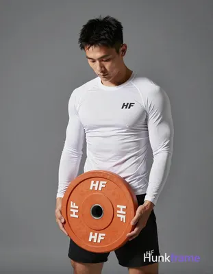 Asian man with light-medium skin and short black textured hair stands in a gym, holding an orange 10