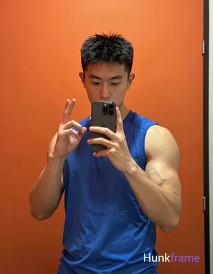 Asian man with short black hair, slightly tousled texture and clean-shaven face stands facing a mirr