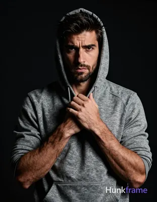 A handsome adult man with medium-dark skin and light stubble stares intensely at