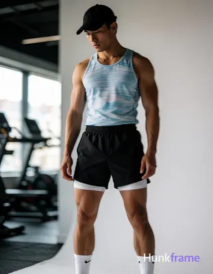 Asian man with light-medium skin standing in a modern home gym, legs spread wide V-shape exposing th