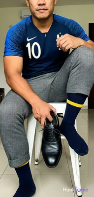 Adult man seated on a white stool, cropped from chest down to knees with head pa
