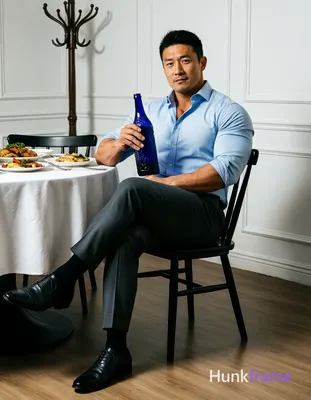 Asian man in muscle bear fine-art photography, seated sideways on black chair wi