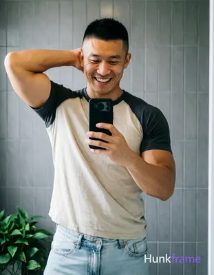 Asian man with short black buzz cut and high fade stands in front of a bathroom 