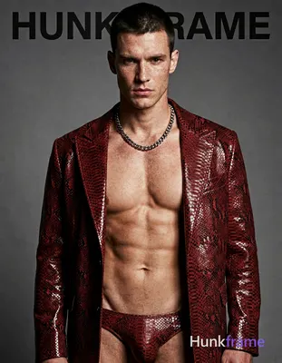 A handsome white man with fair freckled skin and short dark cropped hair stands head-and-shoulders c