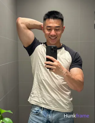 Asian man with short black buzz cut and high fade stands in front of a bathroom 