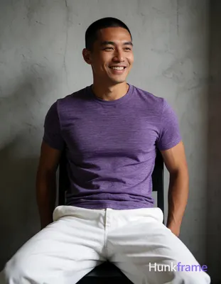 Asian man with short buzz cut and clean-shaven face smiling, seated upright on a