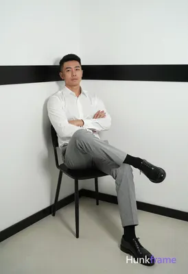 Asian man with short black hair and clean-shaven face, neutral direct gaze seate