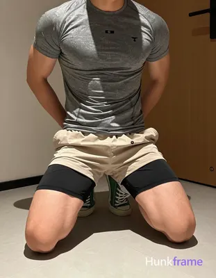 Adult muscular man kneeling on light-colored tiled floor, torso leaning forward slightly with hands 