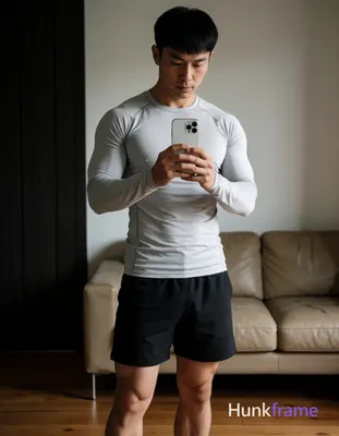 Full-body vertical mirror selfie of an adult Asian man with short black hair and straight bangs, cle