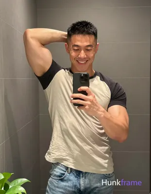Asian man with short black buzz cut and high fade stands in front of a bathroom 