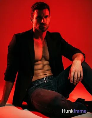 Confident adult man in tasteful suggestive framing, seated with right leg bent and left extended und