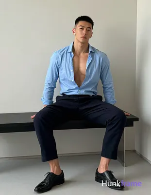 Asian adult man with short black buzz cut and clean-shaven face, seated upright on a modern black be
