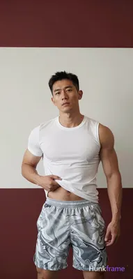 Asian man with short dark hair parted left and clean-shaven face stands center-left in a vertical po