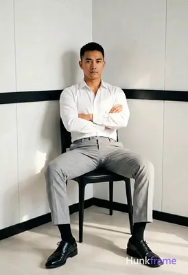 Asian man with short black hair and clean-shaven face, neutral direct gaze seate