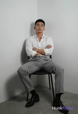 Asian man with short black hair and clean-shaven face, neutral direct gaze seated in a minimalist co