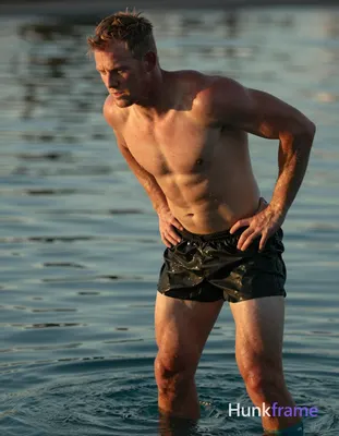 Irish man with pale skin and red undertones, shirtless near a serene pool at sun