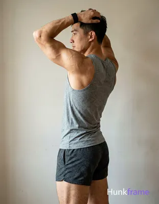 A handsome masculine man as a Xiaohongshu fitness influencer, standing in profile with left arm rais